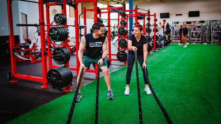 couple using battle ropes for circuit training on functional turf area in monroe health club