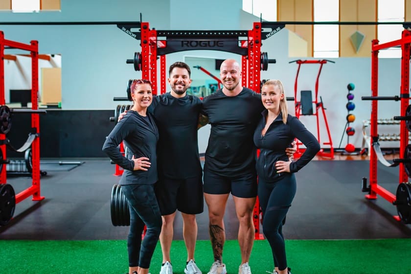 4 staff members dressed in black stand in the turf strength training area at a gym in monroe